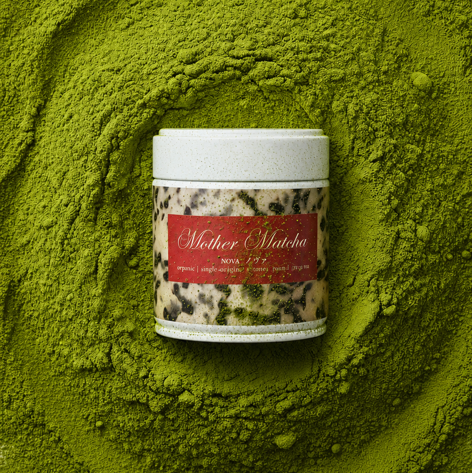 image of a mother matcha tin on a pile of green matcha powder. the tin has a cream and black tortoise shell print on it with a red label around it.